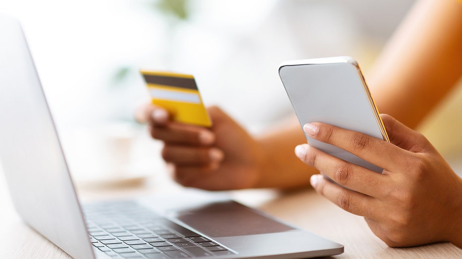 A woman holding a credit card and phone